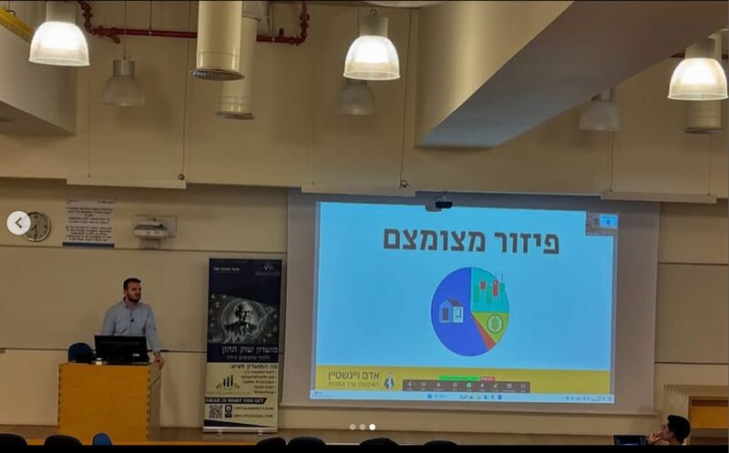 אדם ויינשטיין מרצה על פיזור תיק השקעות מול קהל באולם הרצאות